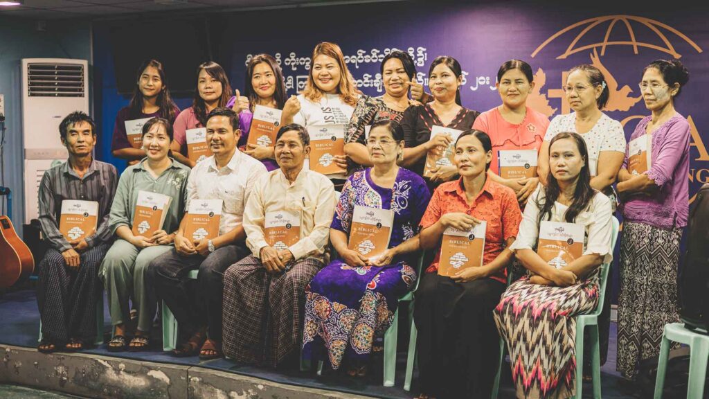 ABC Bible and Leadership Curriculum graduates holding their course materials in Myanmar.