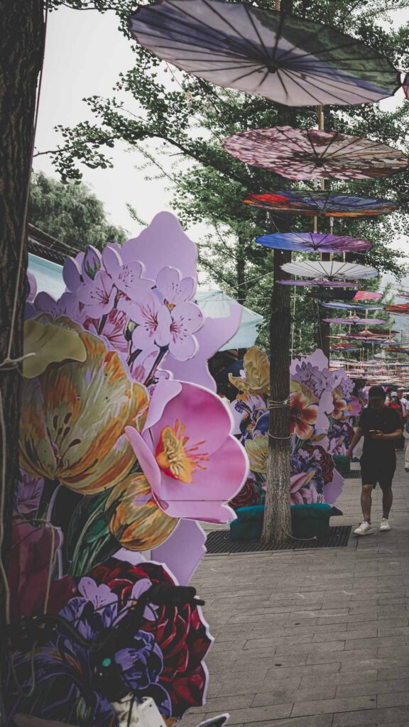Decorative umbrellas and floral displays lining a pedestrian street in Beijing, China.