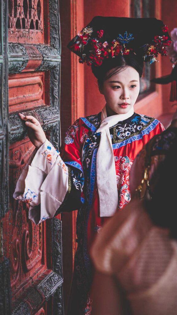 Young woman wearing ornate traditional-style Chinese dress at the Forbidden City in Beijing, China.
