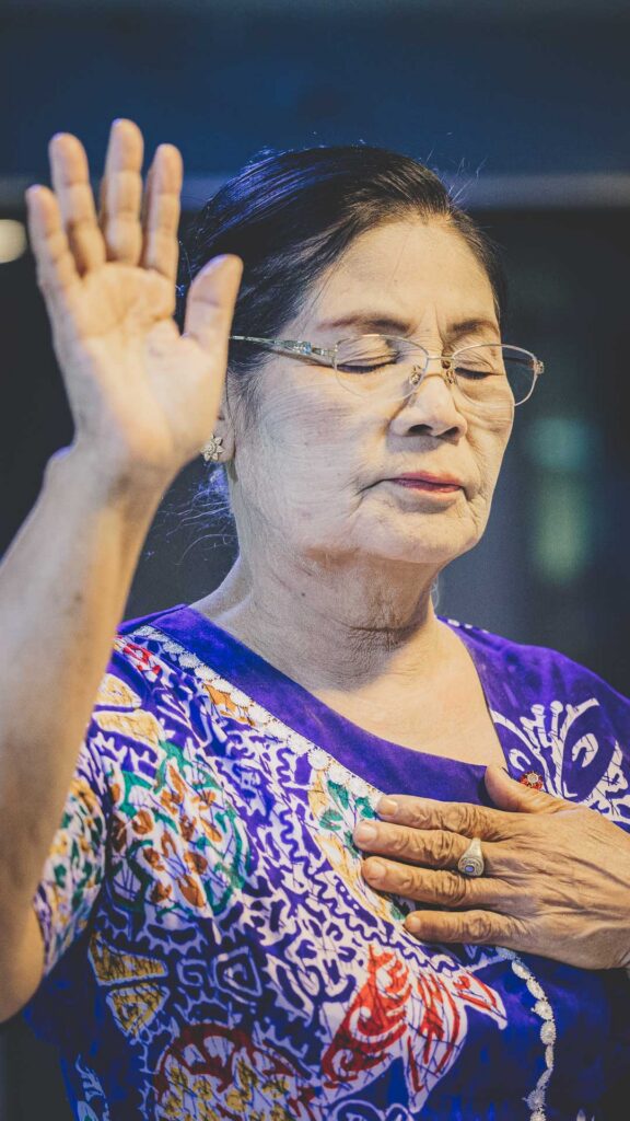 Christian woman worshiping during a local church gathering in Myanmar.