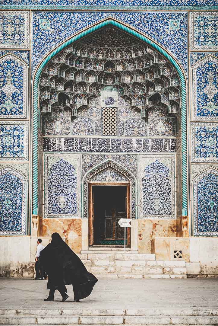 A woman walks past the ornate entrance of the Shah Mosque in Isfahan, Iran.