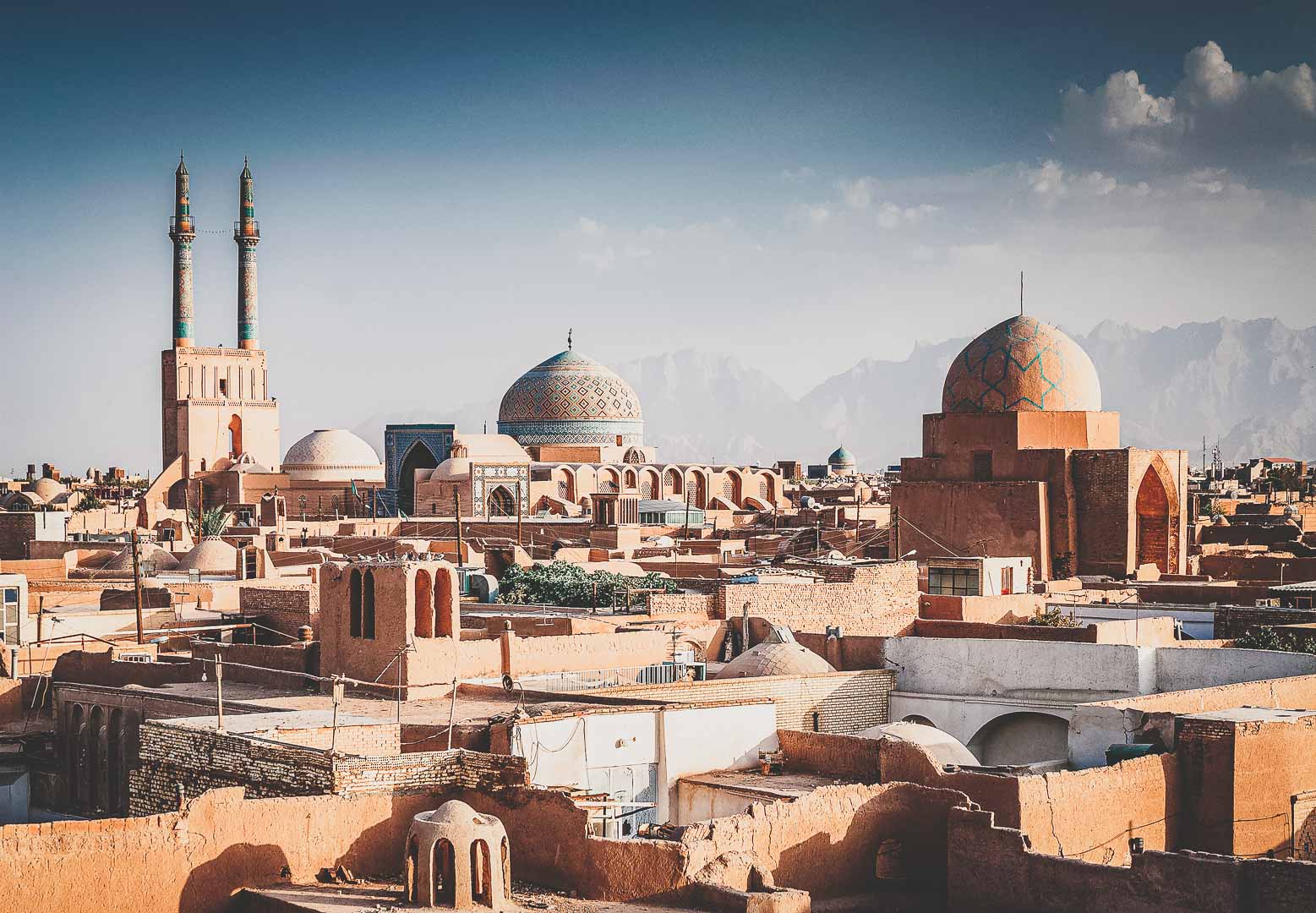 Historic skyline of Yazd, Iran, with mosque domes and minarets rising above the old city.