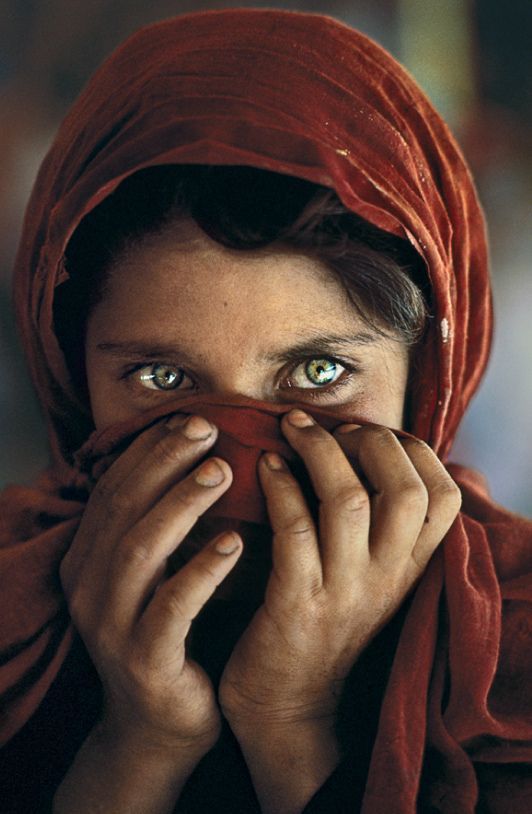 Young girl in Iraq wearing a red headscarf and looking toward the camera.
