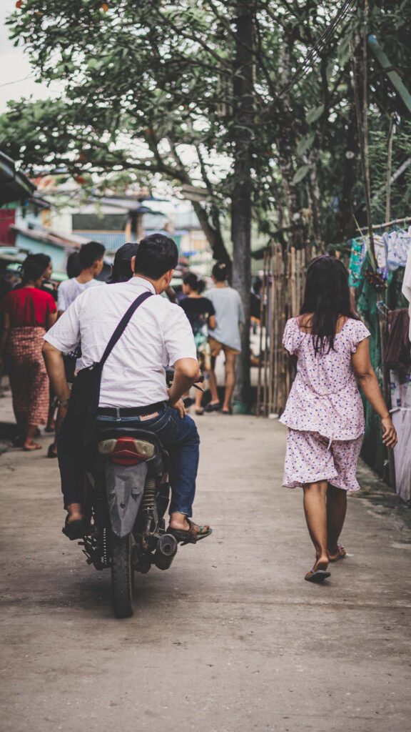 Local pastor traveling by motorbike through a neighborhood to visit ABC classes in Myanmar.