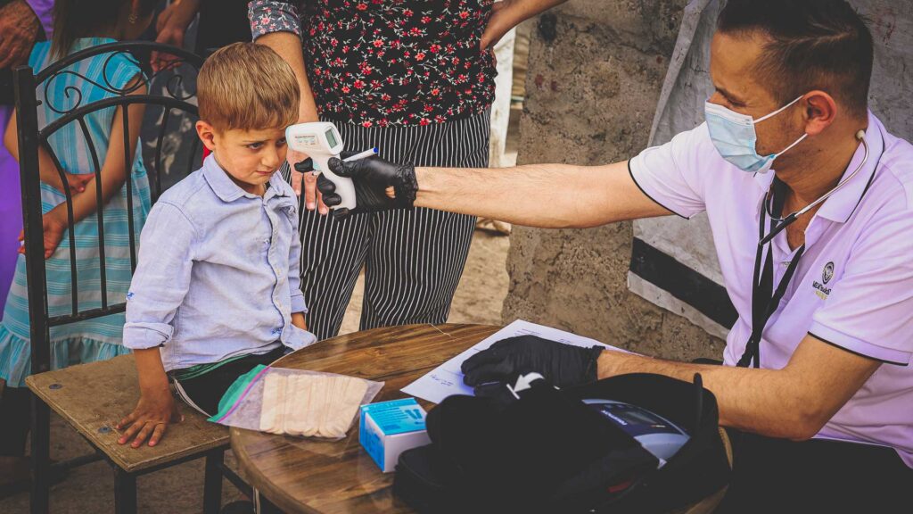 Healthcare worker checking a young child during a Mobile Medical Clinic in Iraq.