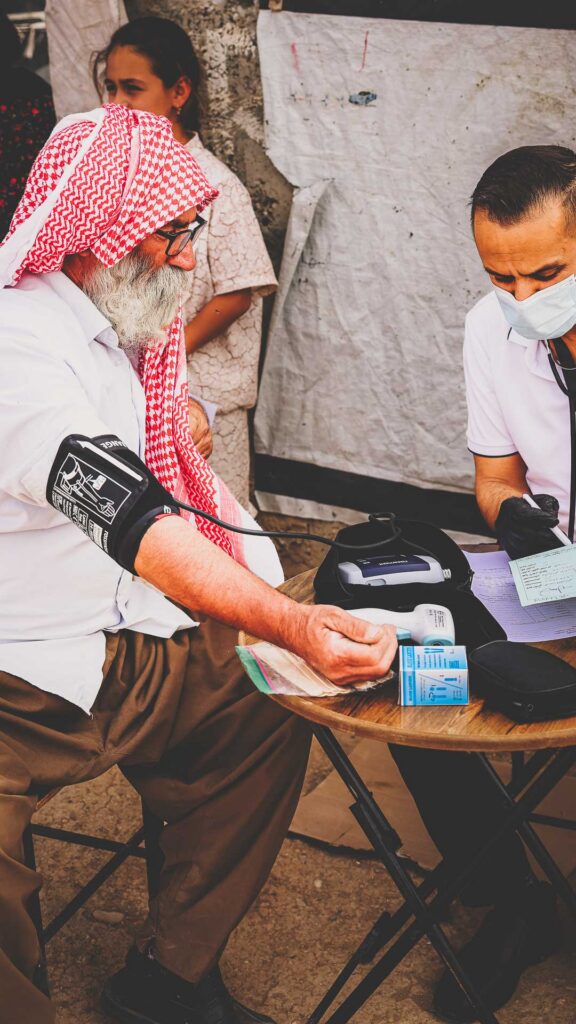 Healthcare worker checking a patient’s blood pressure at a Mobile Medical Clinic in Iraq.