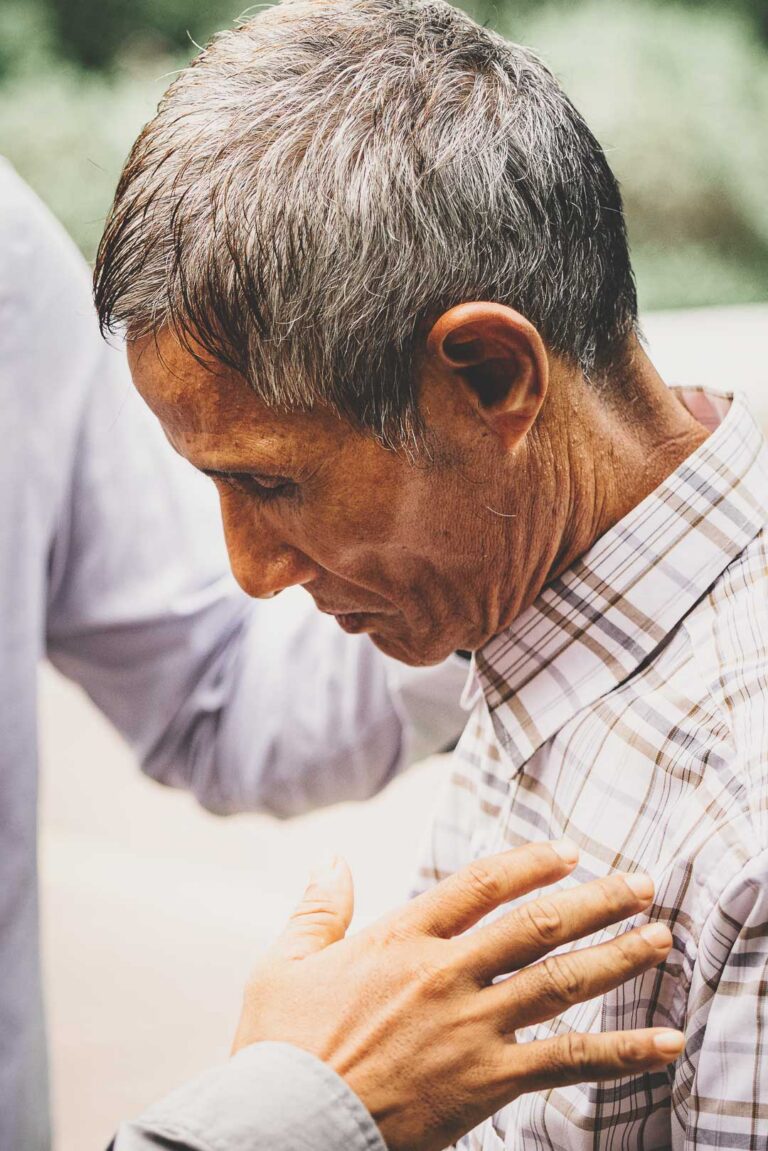 Christian man bowing his head in prayer in Myanmar.