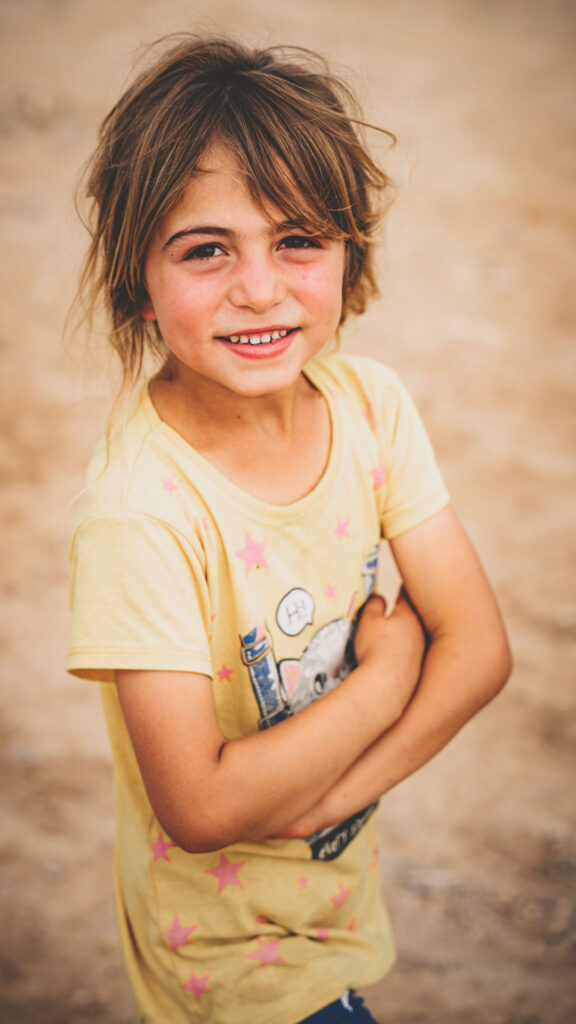 Young girl smiling outdoors in Iraq.