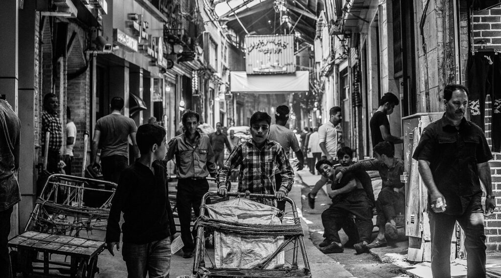 People walking through a busy market street in Iran.
