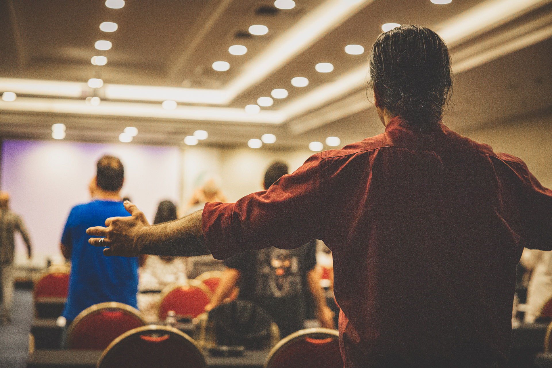 Person standing with arms extended during a gathering.