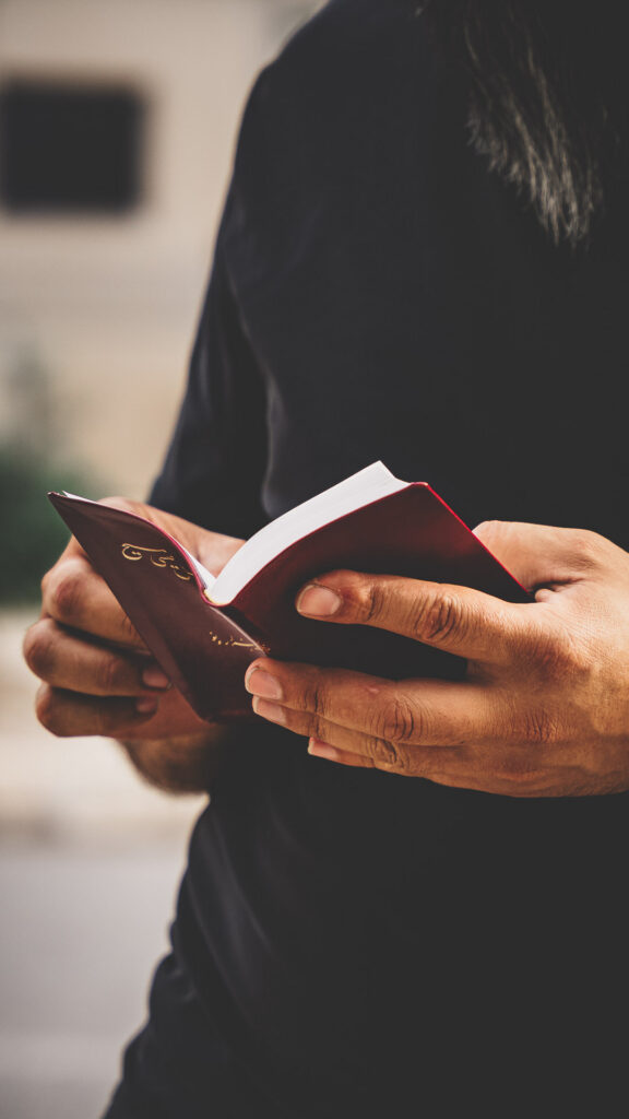 Person holding and reading a Farsi-language Bible.
